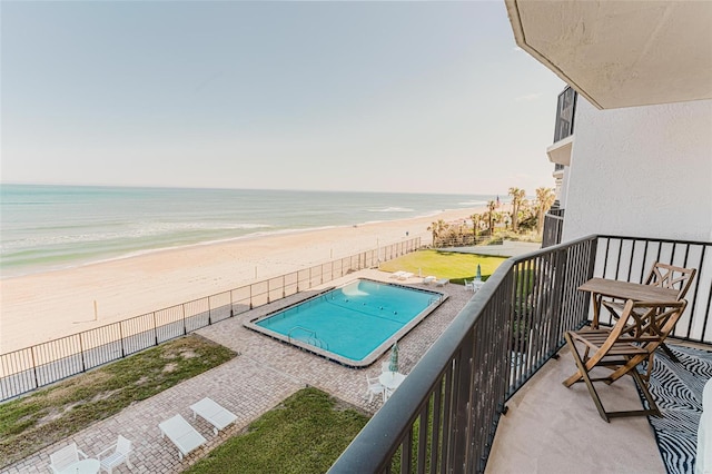 balcony with a water view and a view of the beach