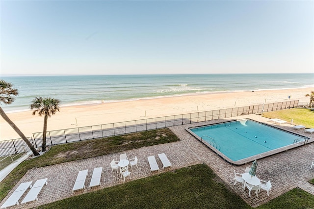 view of swimming pool featuring a yard, a beach view, and a water view