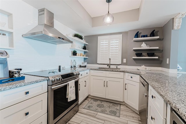 kitchen with sink, island range hood, stainless steel appliances, light stone countertops, and white cabinets