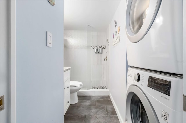 bathroom featuring vanity, a shower, toilet, and stacked washing maching and dryer