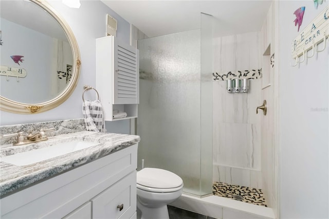 bathroom featuring vanity, tiled shower, and toilet