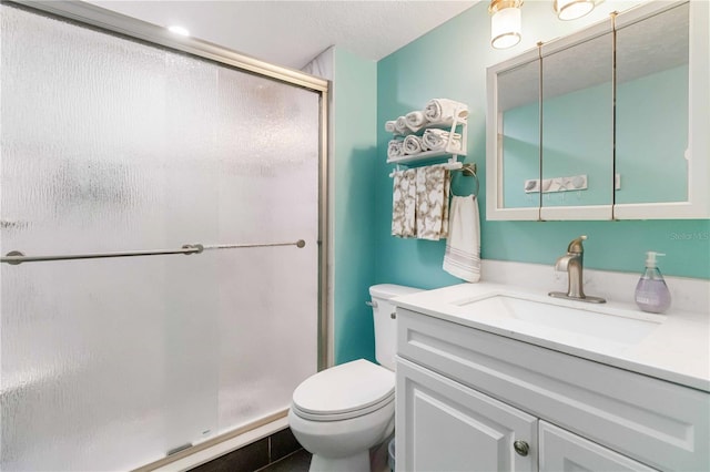 bathroom with vanity, a shower with shower door, and toilet