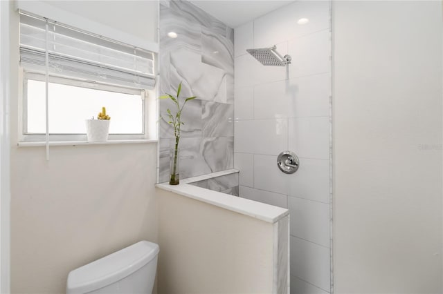 bathroom featuring tiled shower and toilet