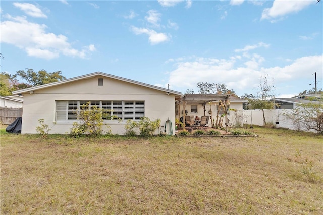 back of property with a yard and a pergola