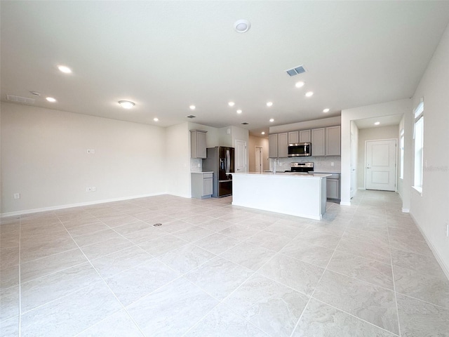 kitchen featuring stainless steel appliances, a kitchen island with sink, sink, and gray cabinets