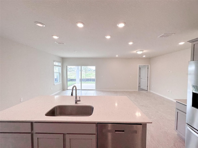 kitchen with stainless steel appliances, light stone countertops, sink, and gray cabinetry