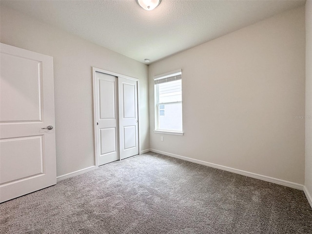 unfurnished bedroom featuring carpet floors, a closet, and a textured ceiling