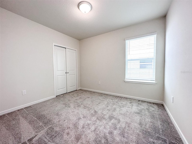 unfurnished bedroom with a closet, light carpet, and a textured ceiling