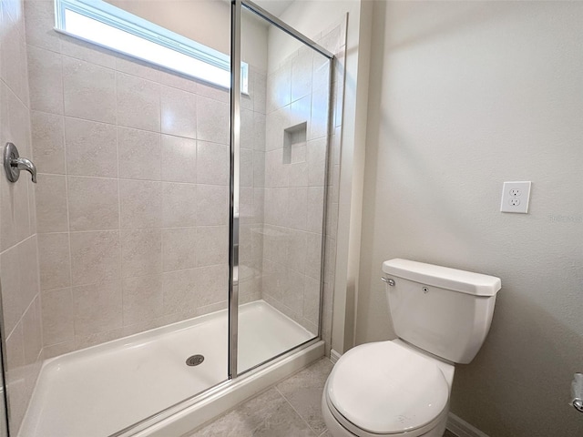 bathroom with a shower with door and toilet