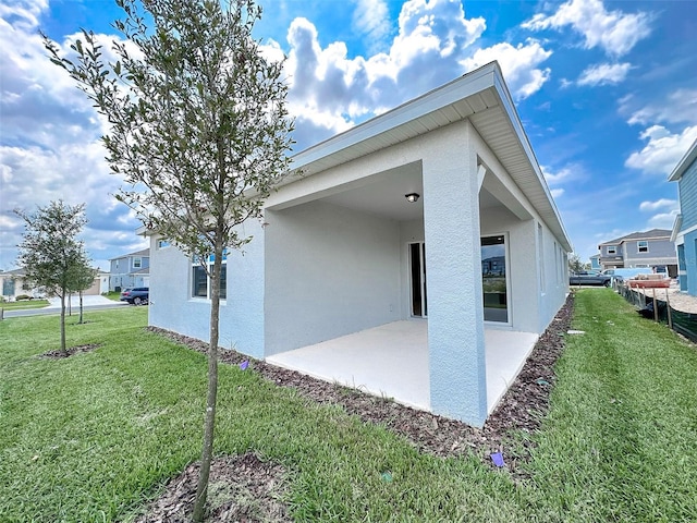 view of property exterior with a patio and a lawn