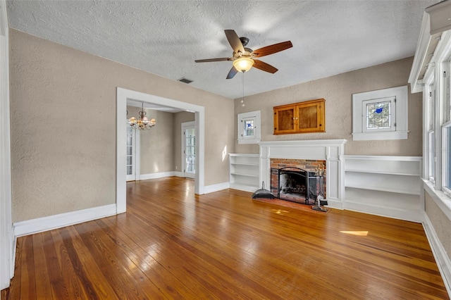 unfurnished living room with a textured wall, hardwood / wood-style floors, a fireplace, and visible vents