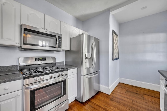 kitchen with white cabinetry, baseboards, appliances with stainless steel finishes, dark countertops, and dark wood finished floors