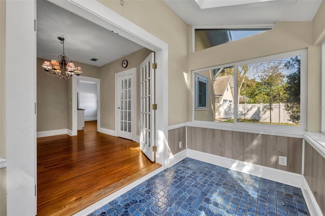 interior space with baseboards, a notable chandelier, and wood finished floors