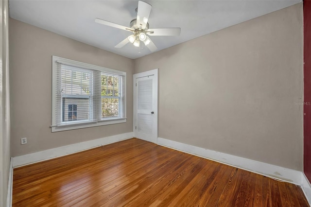 empty room with a ceiling fan, baseboards, and hardwood / wood-style floors