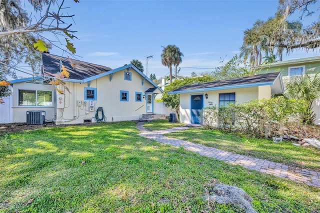 back of property featuring a lawn, stucco siding, and central air condition unit