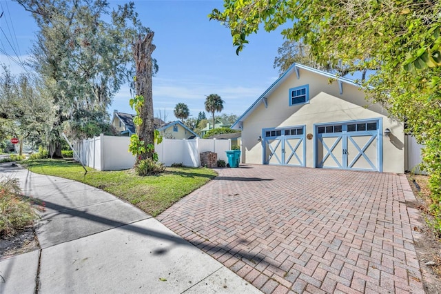 exterior space with a garage, fence, decorative driveway, stucco siding, and a front yard