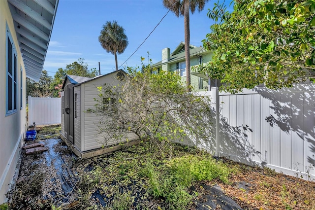 view of yard featuring a storage shed, an outdoor structure, and a fenced backyard