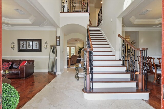 entrance foyer featuring arched walkways, a tray ceiling, visible vents, and crown molding