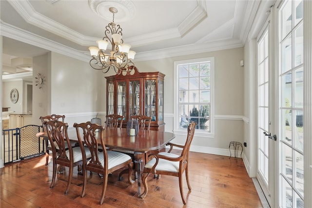 dining space with a notable chandelier, wood finished floors, baseboards, french doors, and crown molding