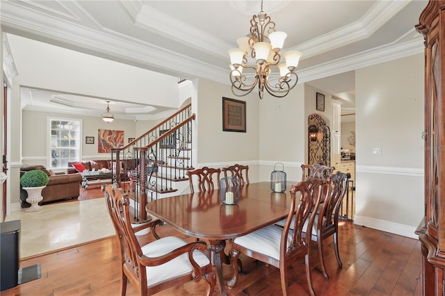 dining space featuring a raised ceiling, stairway, dark wood-style flooring, and an inviting chandelier