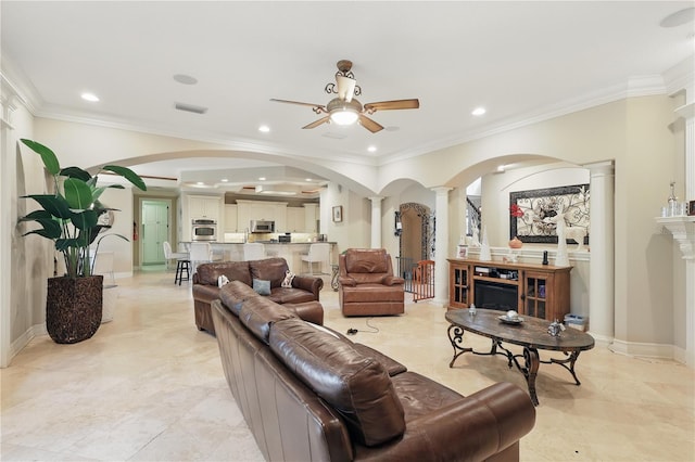 living room featuring arched walkways, crown molding, visible vents, ceiling fan, and ornate columns