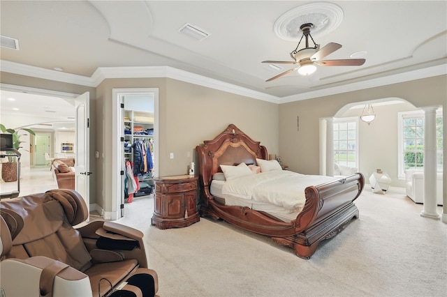 bedroom with decorative columns, visible vents, arched walkways, and light colored carpet