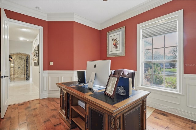 office area with light wood-type flooring, wainscoting, crown molding, and a decorative wall