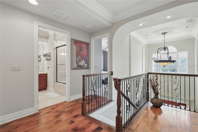 hall featuring visible vents, crown molding, an upstairs landing, and wood finished floors