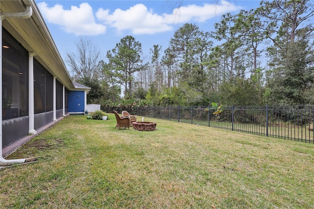 view of yard featuring a sunroom, a fenced backyard, and a fire pit