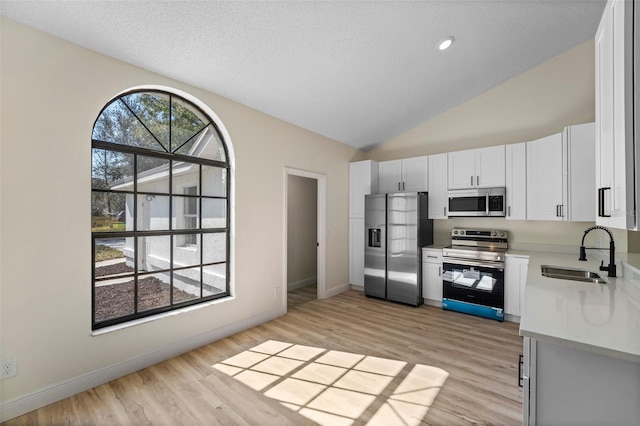 kitchen with sink, stainless steel appliances, light hardwood / wood-style floors, a textured ceiling, and white cabinets