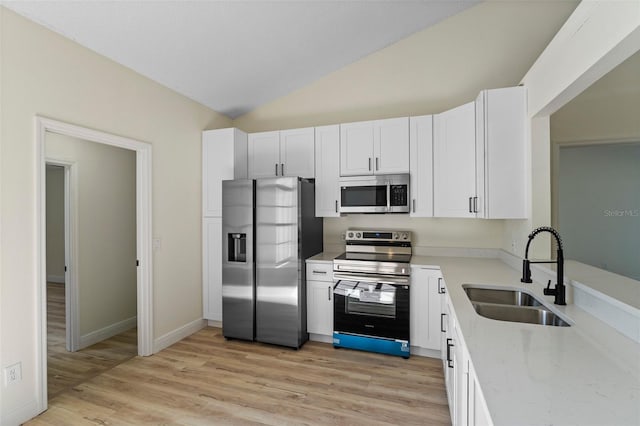 kitchen with sink, white cabinetry, vaulted ceiling, light hardwood / wood-style flooring, and stainless steel appliances