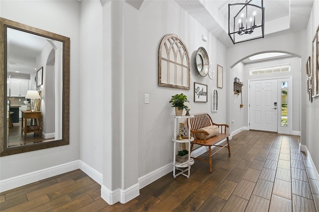 foyer with an inviting chandelier, dark hardwood / wood-style floors, and a raised ceiling