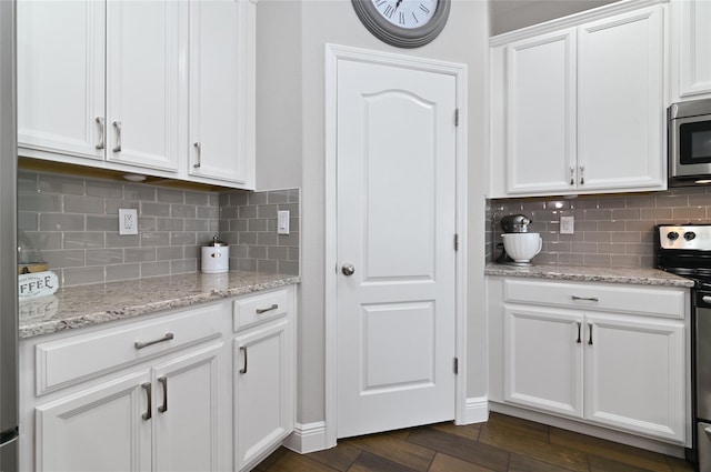 kitchen with white cabinetry, appliances with stainless steel finishes, light stone countertops, and tasteful backsplash