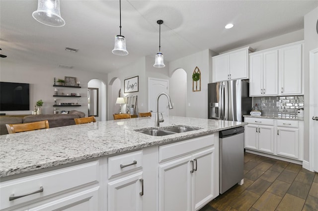 kitchen with sink, decorative light fixtures, white cabinets, stainless steel appliances, and backsplash