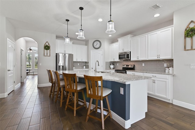 kitchen with sink, white cabinetry, appliances with stainless steel finishes, an island with sink, and pendant lighting