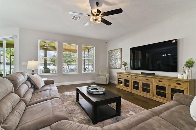 living room with ceiling fan, dark wood-type flooring, and a textured ceiling