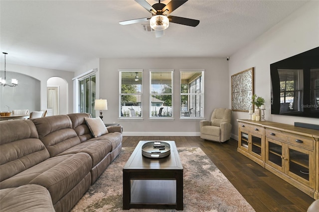 living room featuring dark hardwood / wood-style flooring, ceiling fan with notable chandelier, and a textured ceiling