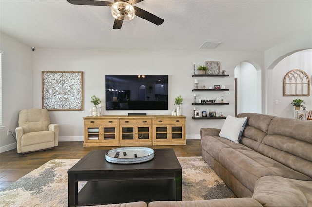 living room with ceiling fan, dark wood-type flooring, and a textured ceiling