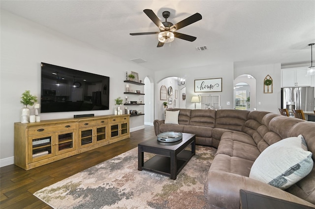 living room featuring ceiling fan, dark hardwood / wood-style floors, and a textured ceiling