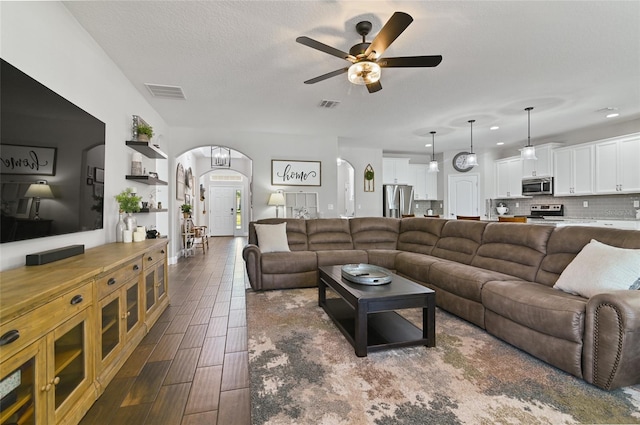 living room featuring ceiling fan, dark hardwood / wood-style floors, and a textured ceiling