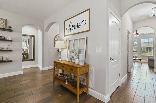 hall with a textured ceiling and dark hardwood / wood-style flooring