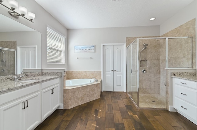 bathroom with vanity, shower with separate bathtub, hardwood / wood-style floors, and a textured ceiling