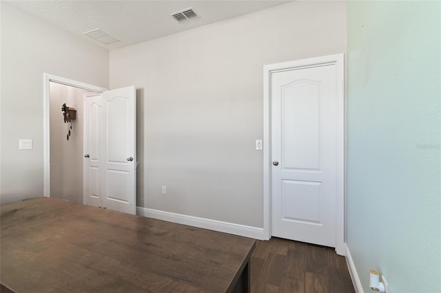 unfurnished room featuring dark wood-type flooring and a textured ceiling