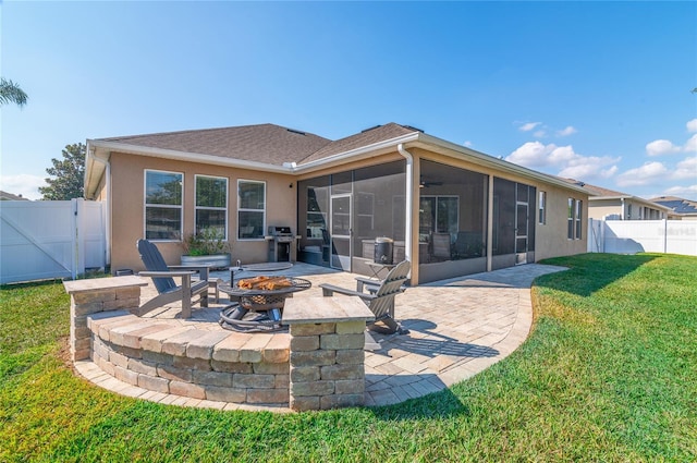 back of property with a patio, a sunroom, a yard, and an outdoor fire pit