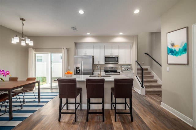 kitchen with stainless steel appliances, decorative light fixtures, sink, and white cabinets