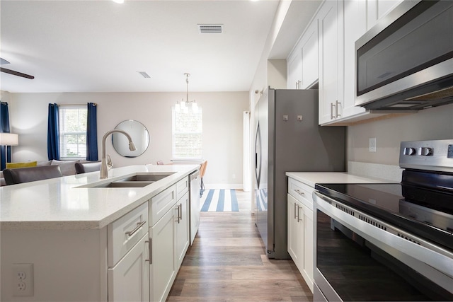 kitchen featuring white cabinetry, appliances with stainless steel finishes, sink, and hanging light fixtures