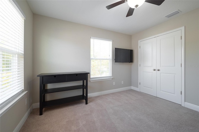 bedroom featuring light colored carpet, ceiling fan, and a closet