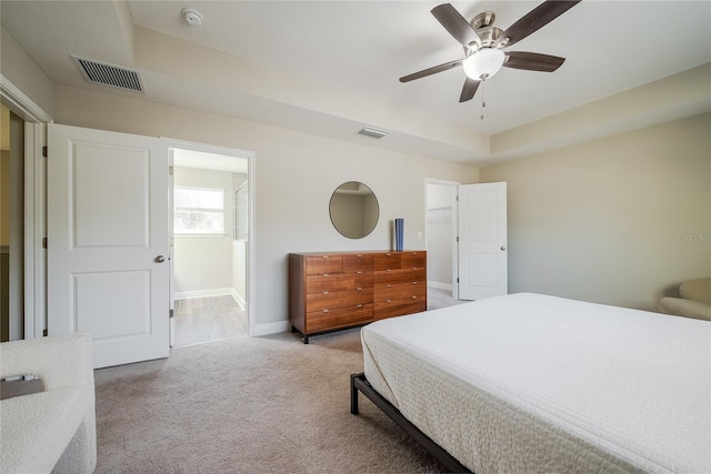 carpeted bedroom featuring a raised ceiling and ceiling fan