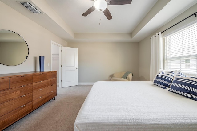 carpeted bedroom featuring ceiling fan and a raised ceiling