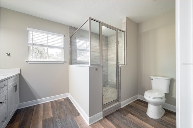 bathroom with hardwood / wood-style flooring, vanity, toilet, and a shower with door